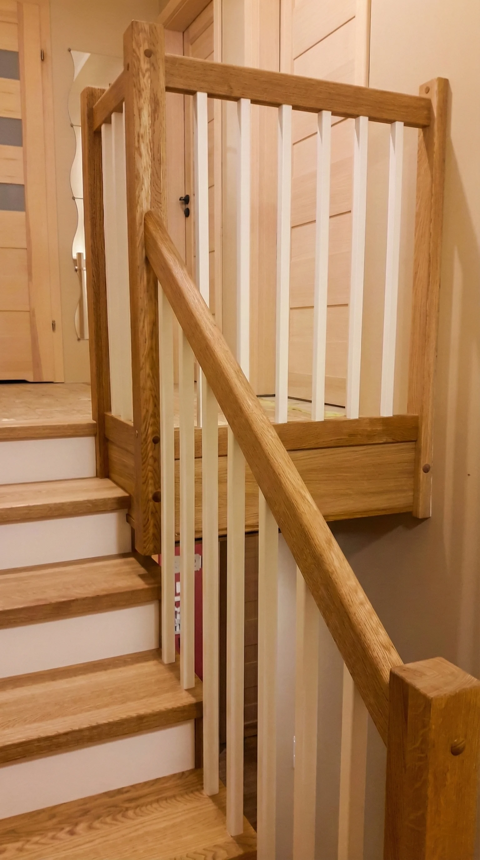Widok schodów wewnątrz domu, połączenie drewna i bieli