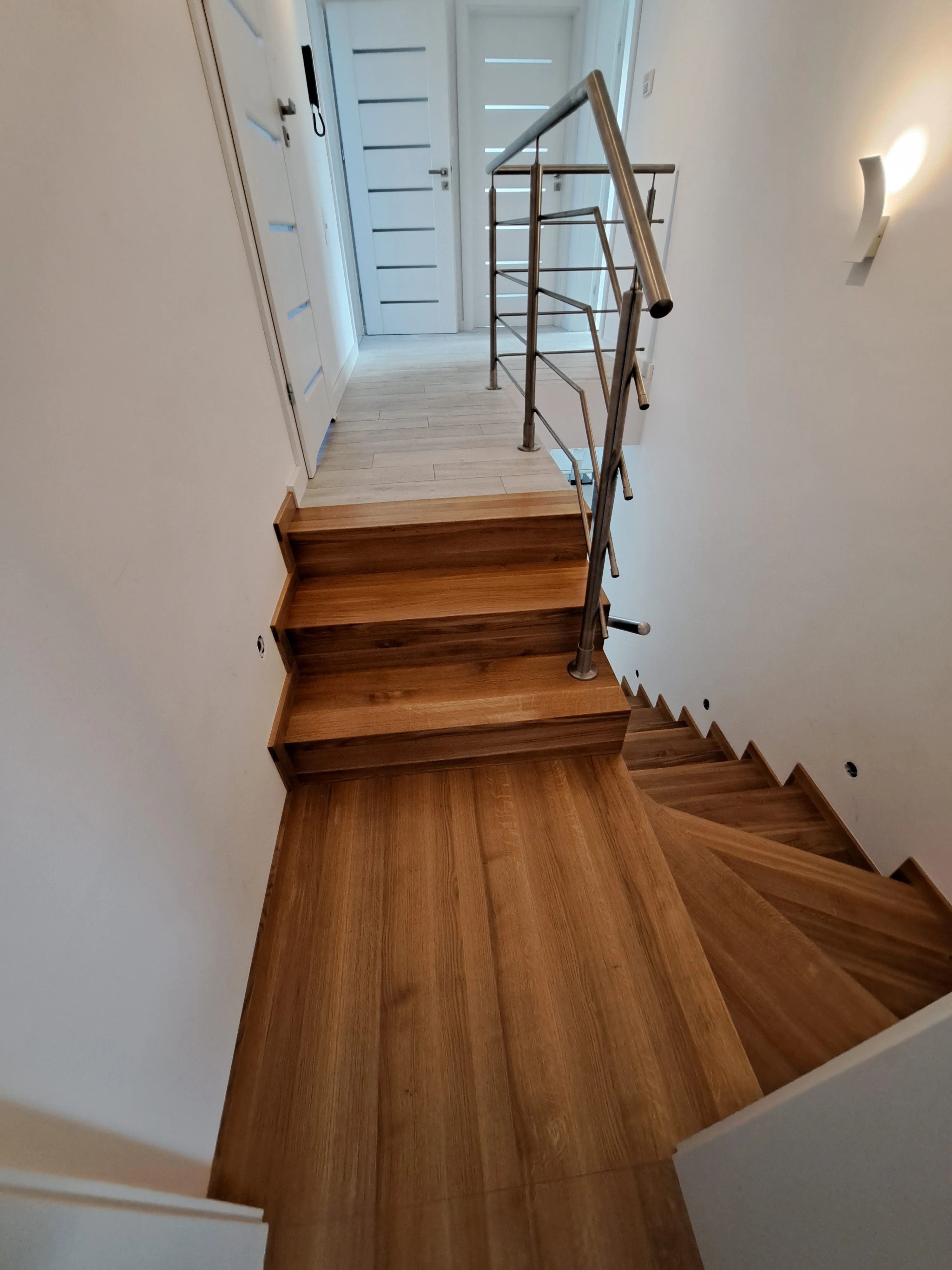 Całościowy widok klatki schodowej, połączenie dębu i stali nierdzewnej