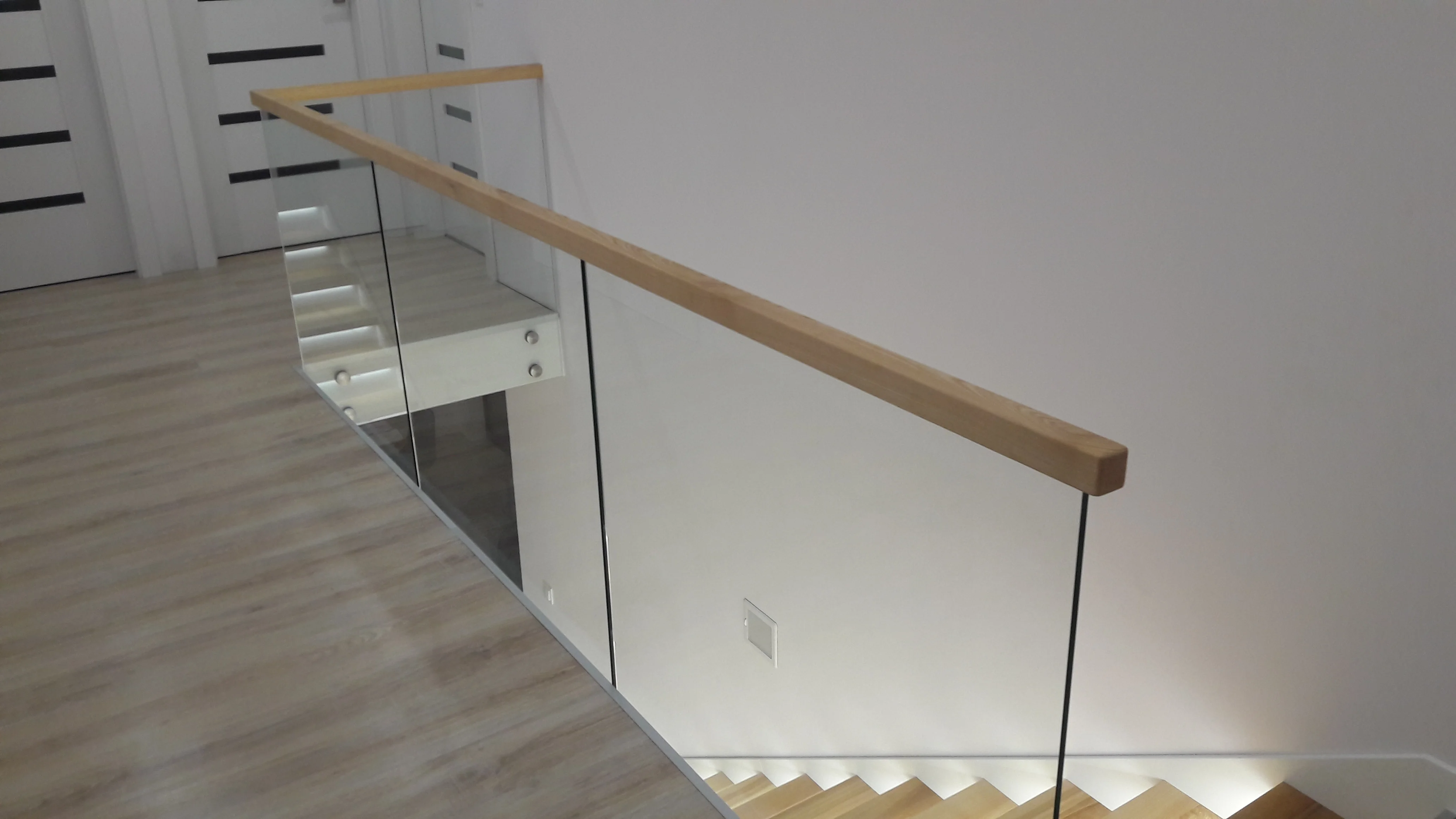 Detal balustrady szklanej samonośnej przy schodach jesionowych